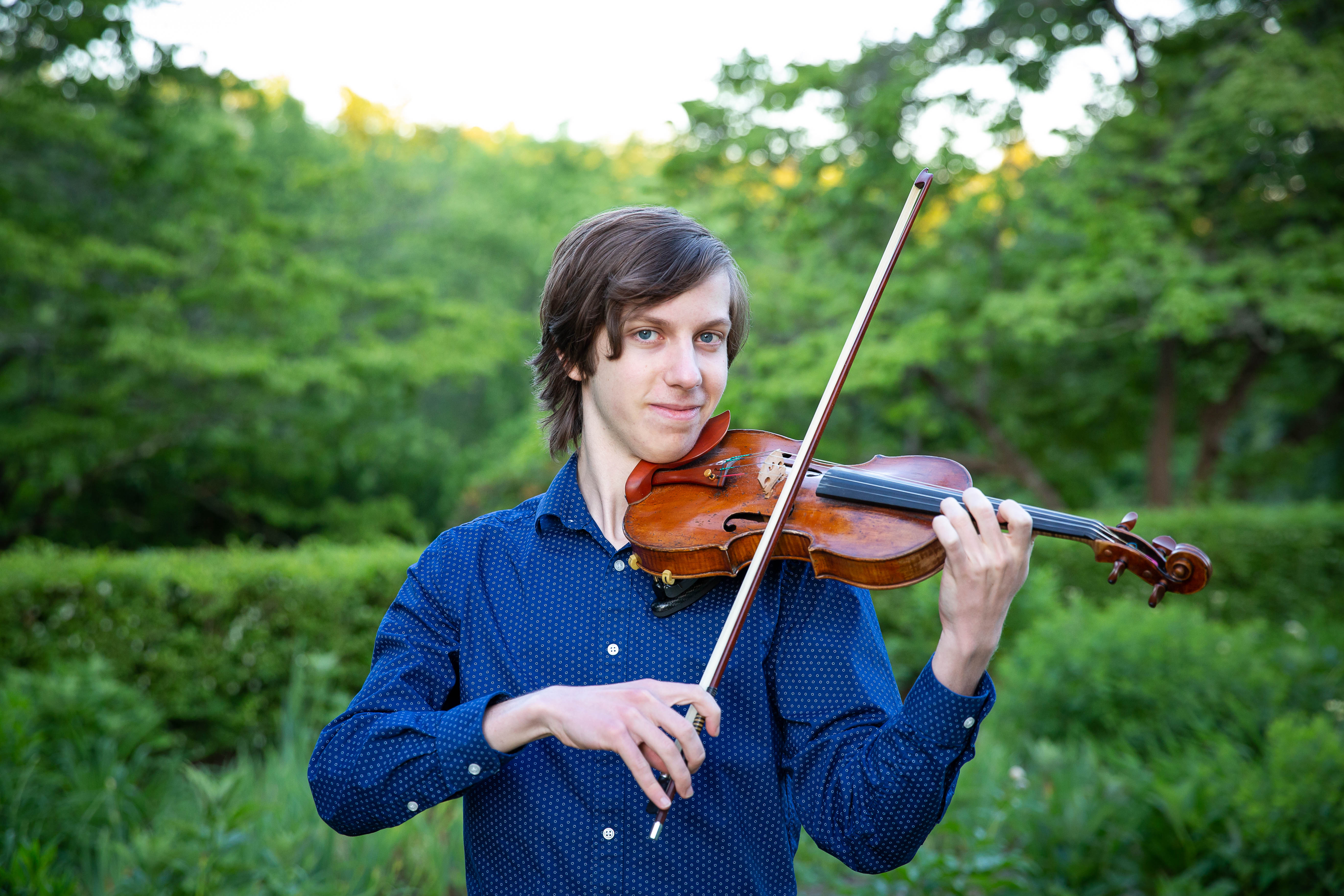 Myself holding my violin in a field